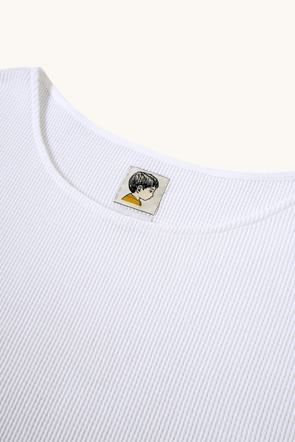 MEG.S white 100% cotton waffle knit long sleeve shirt with a wide neckline and graphic tag.